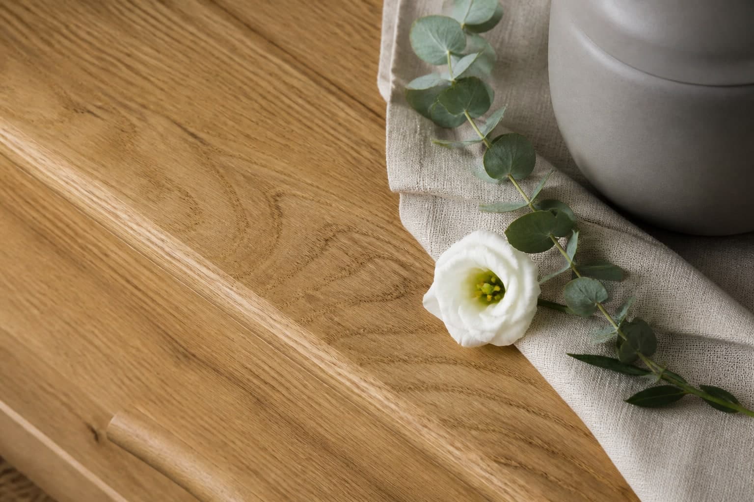 Urne aus hellem Holz mit Leinentuch
