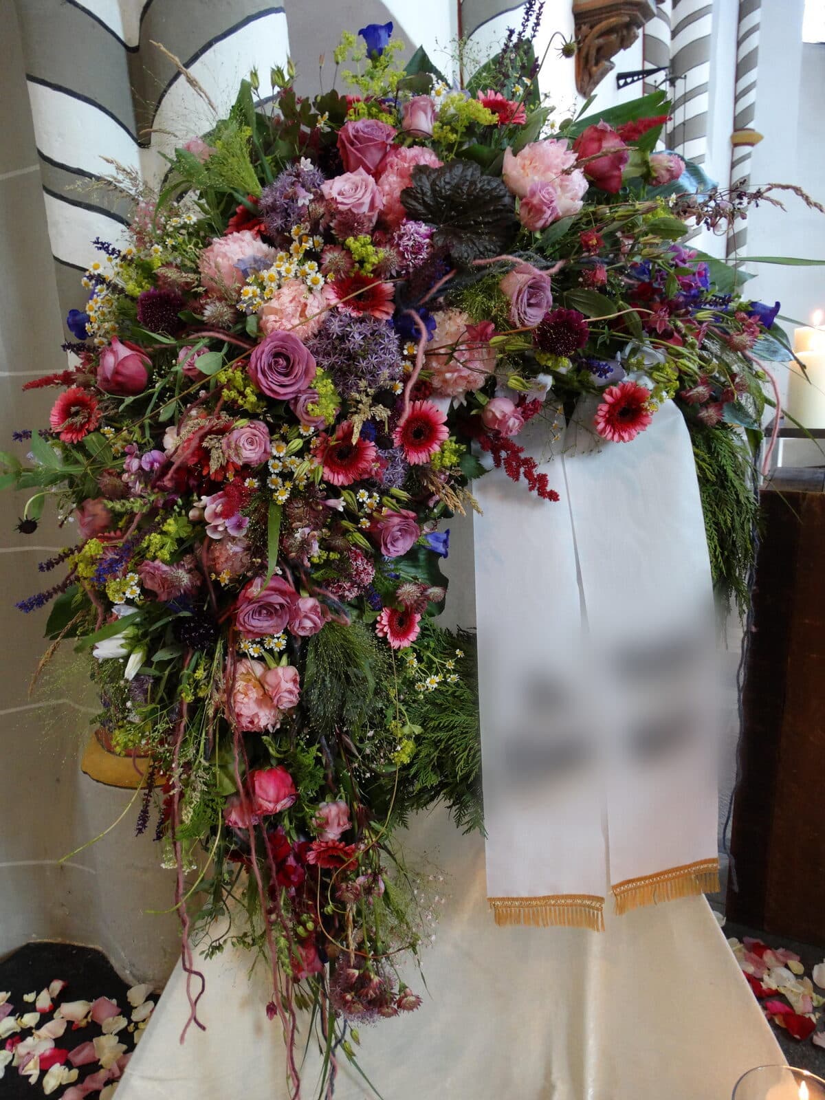 Von uns gebundener Trauerkranz mit Schleife in einer Kirche