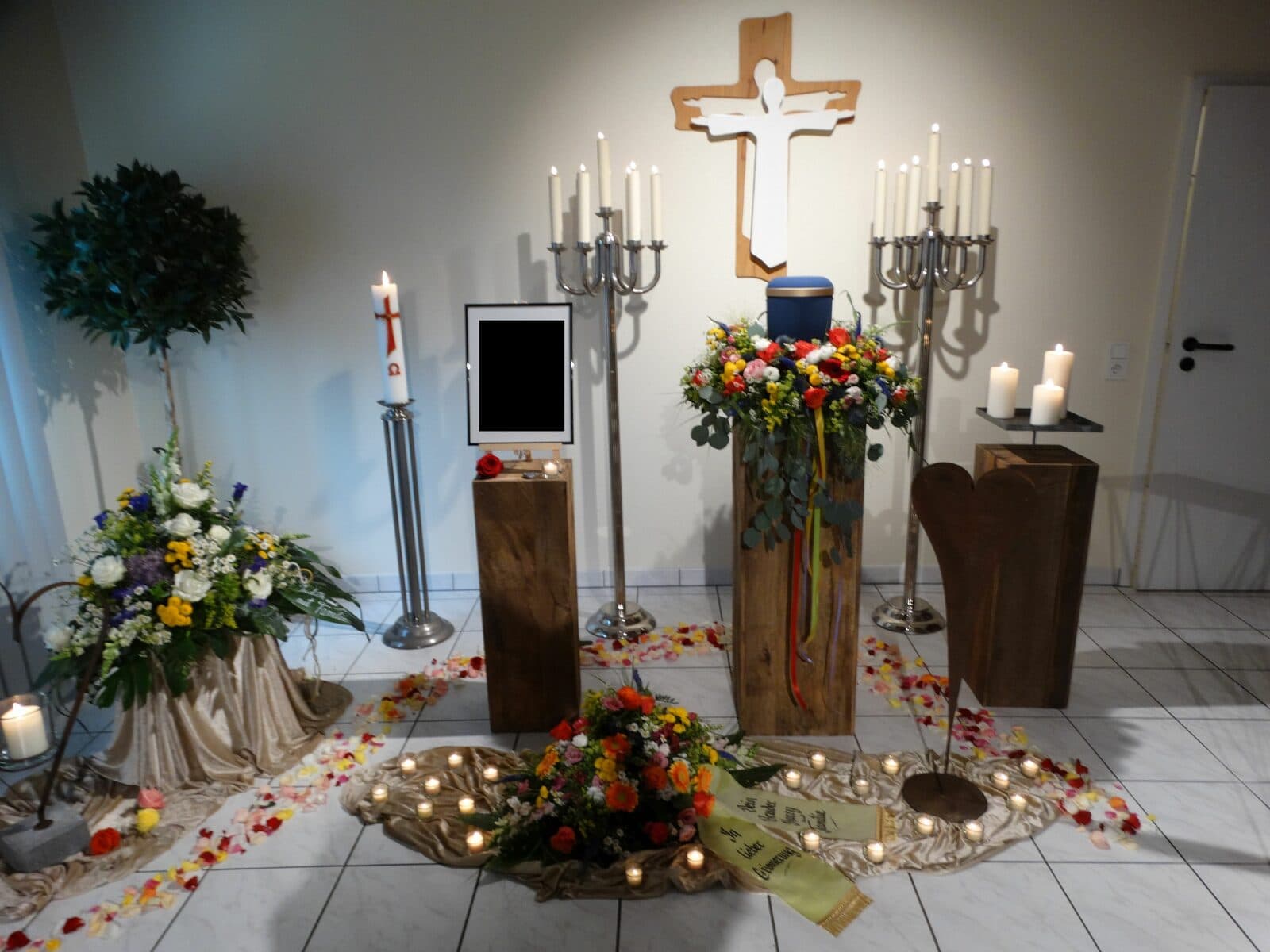 Urnenaufbahrung mit Blumenschmuck und Kerzen im Raum der Stille